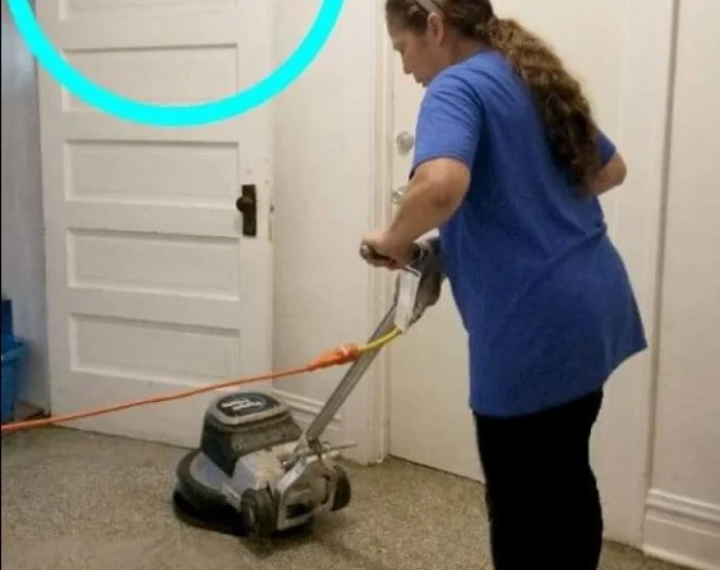 A woman in a blue shirt and black pants operating a floor buffer